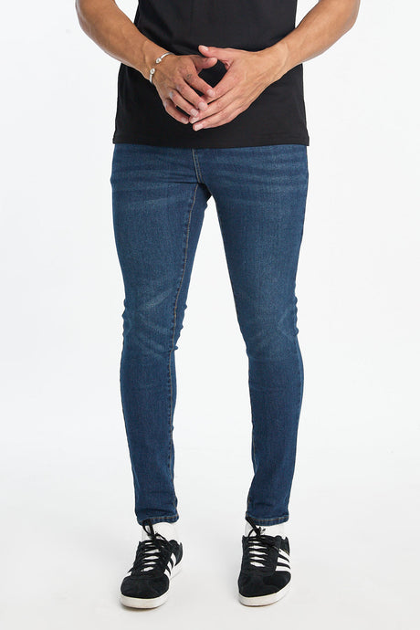 Chase Skinny Jeans in dark blue denim worn with a black t shirt and sneakers.